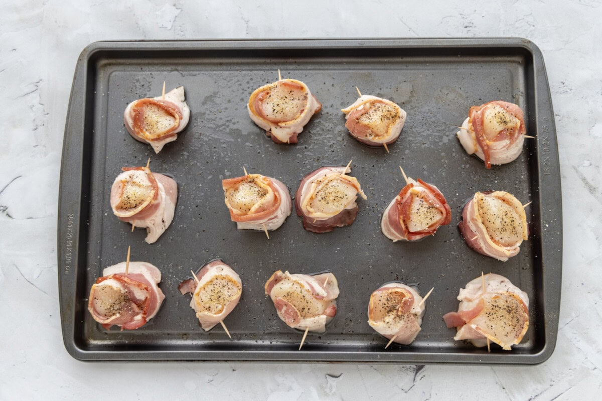 seasoned bacon wrapped scallops on a baking sheet
