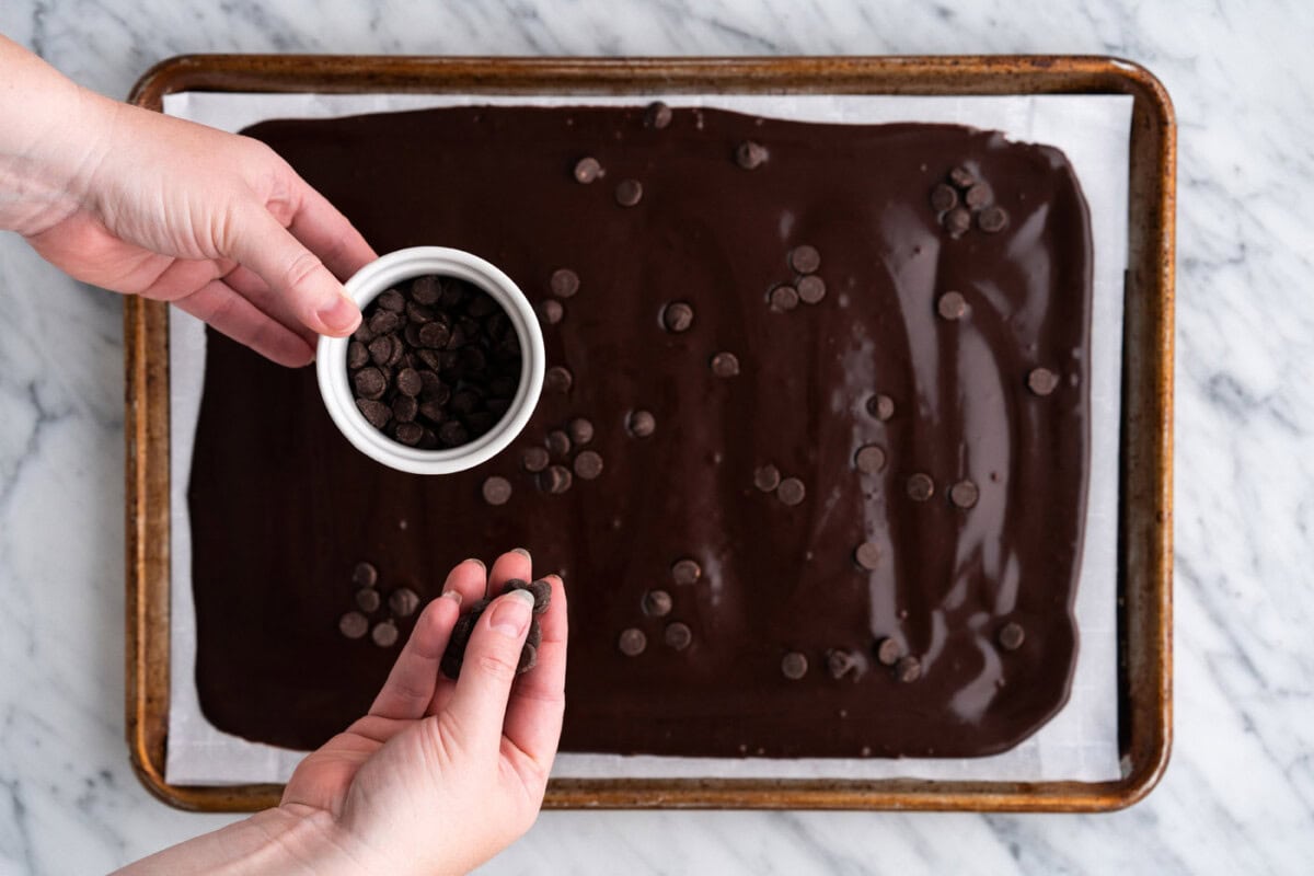 sprinkling chocolate chips over brownie brittle batter