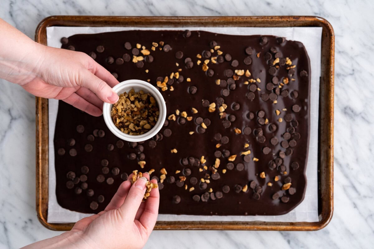 adding chopped nuts on top of brownie brittle