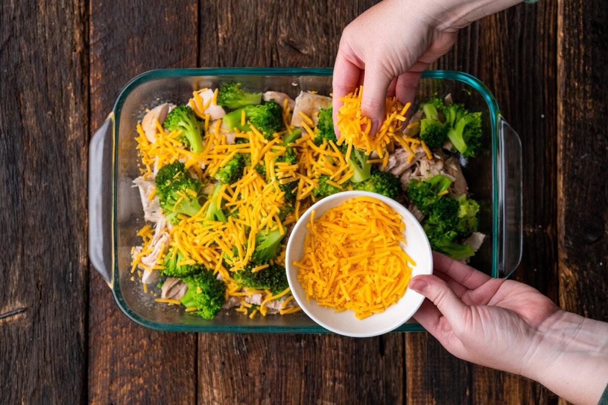 sprinkling cheddar cheese on top of broccoli and cheddar