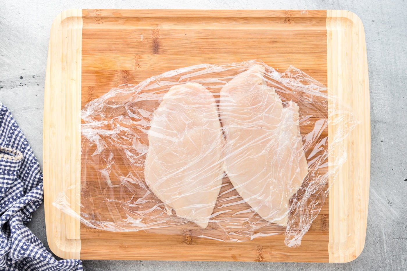 chicken breasts covered with plastic wrap