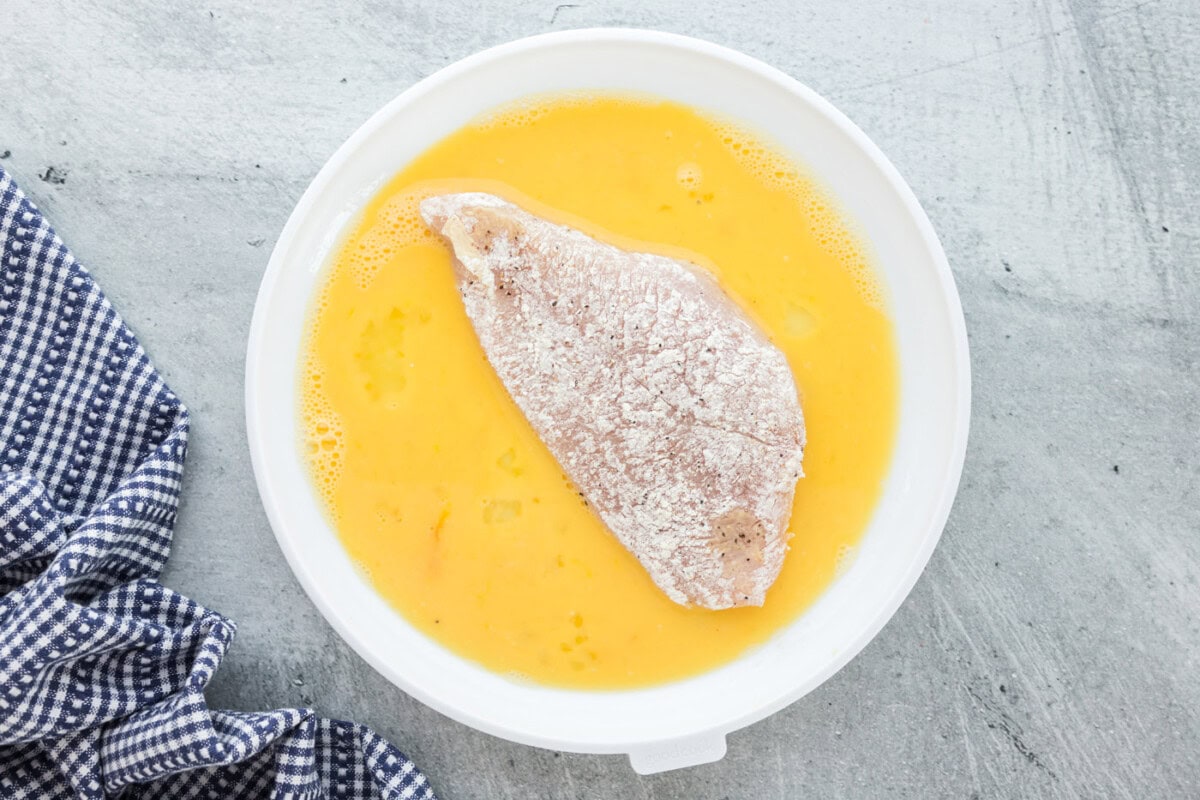 four dredged chicken breasts in egg mixture