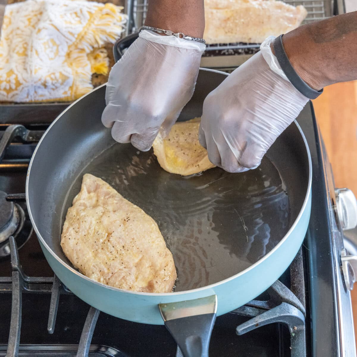 placing chicken breasts into skillet