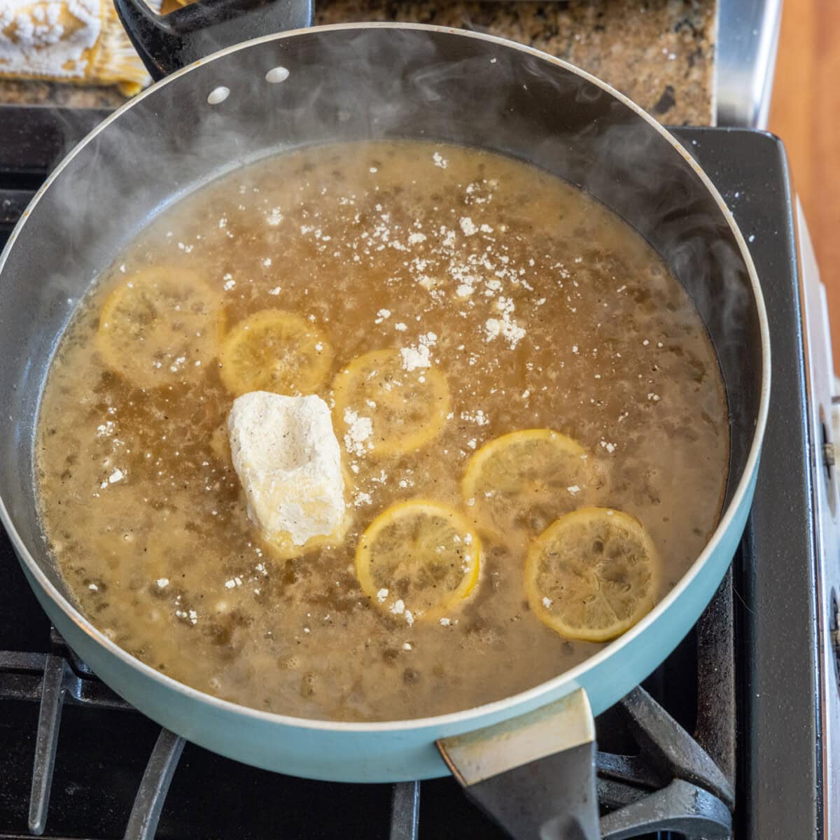 butter coated in flour added to skillet with lemon slices and white wine
