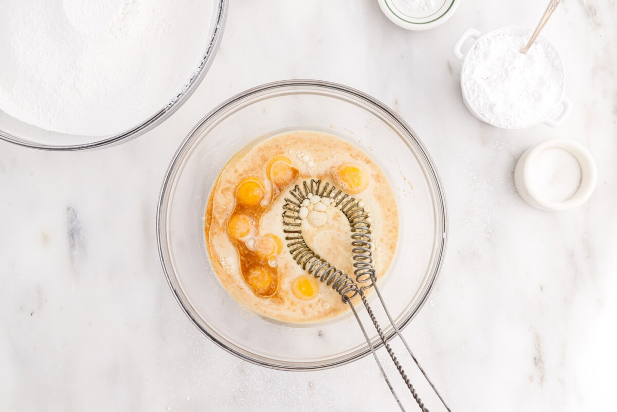 whisking eggs with oil, milk, and extracts