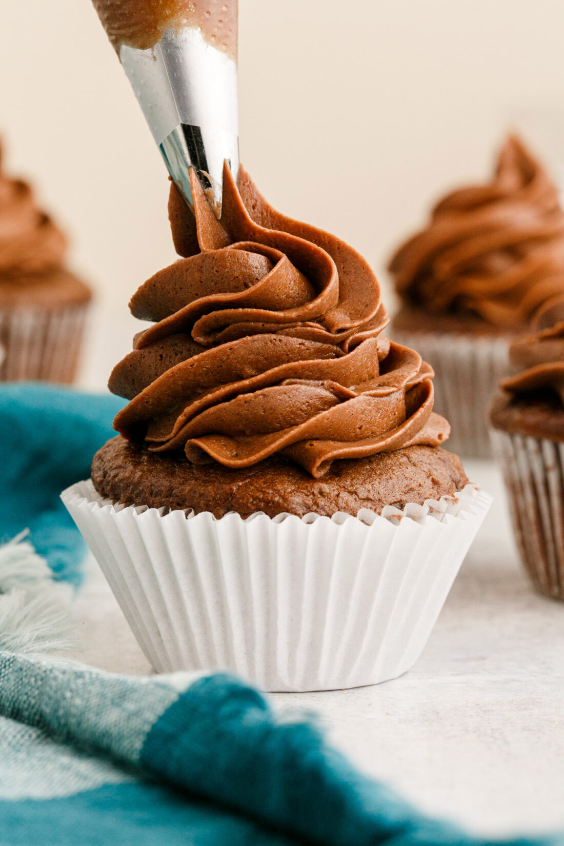 piping Chocolate Buttercream Frosting onto a cupcake