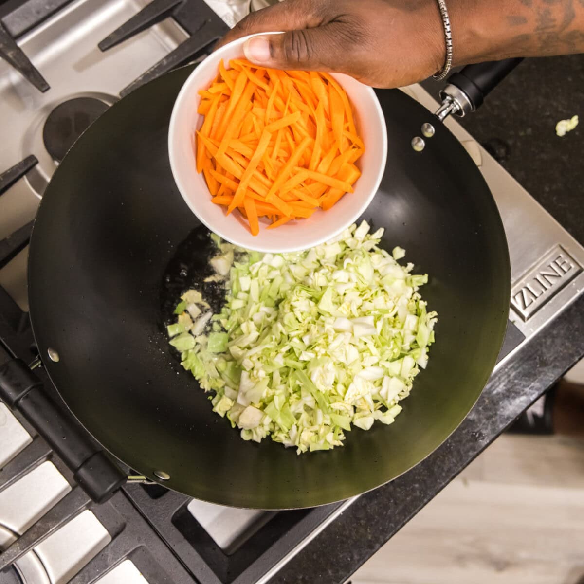 adding carrots with cabbage to a wok