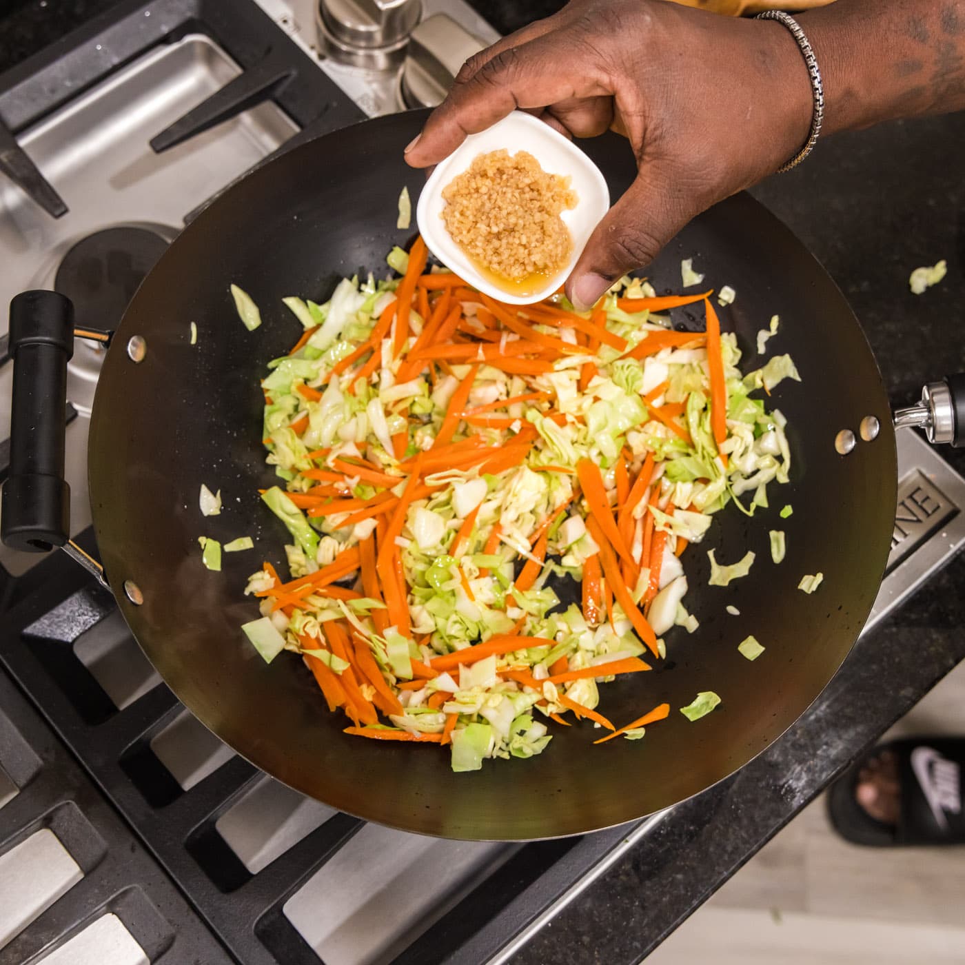 adding garlic to wok with carrot and cabbage