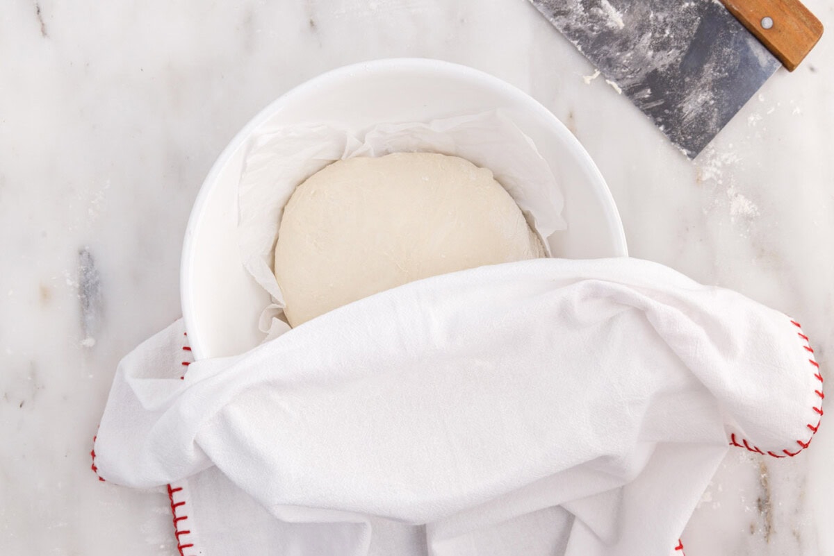 covering dough in a bowl with a towel