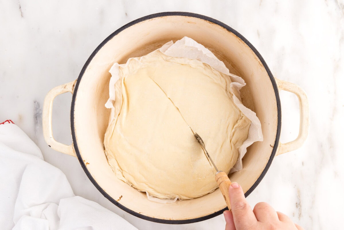 scoring bread dough in a dutch oven