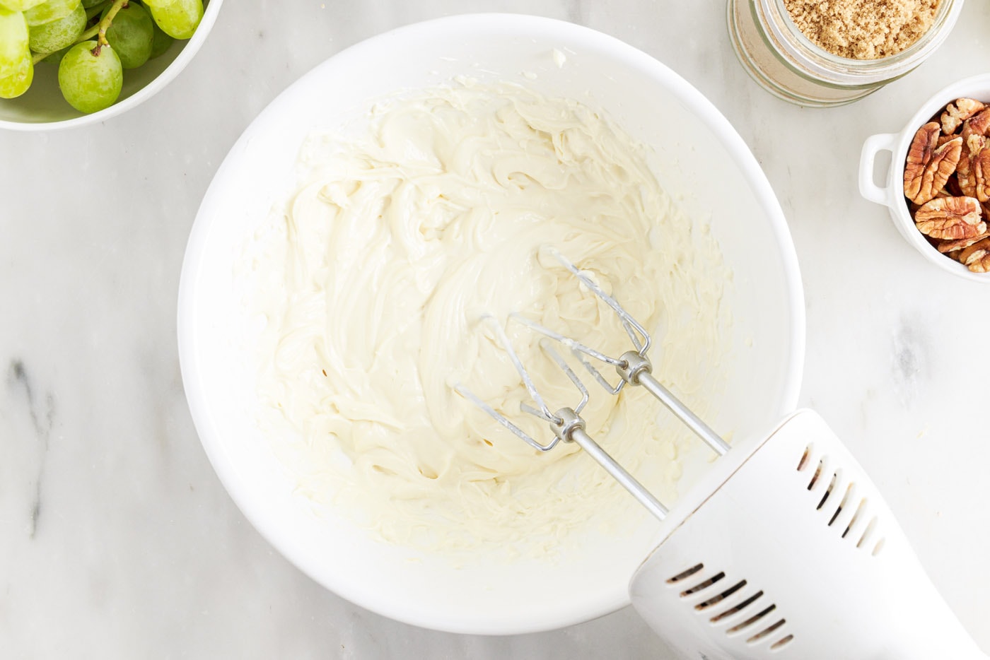 hand mixer beating cream cheese, sour cream, sugar, and vanilla extract