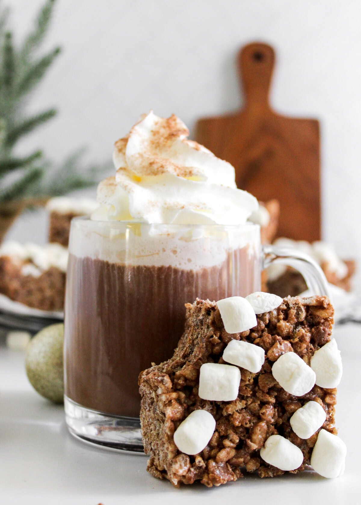 Hot Cocoa Rice Krispie Treats leaning against a mug of cocoa