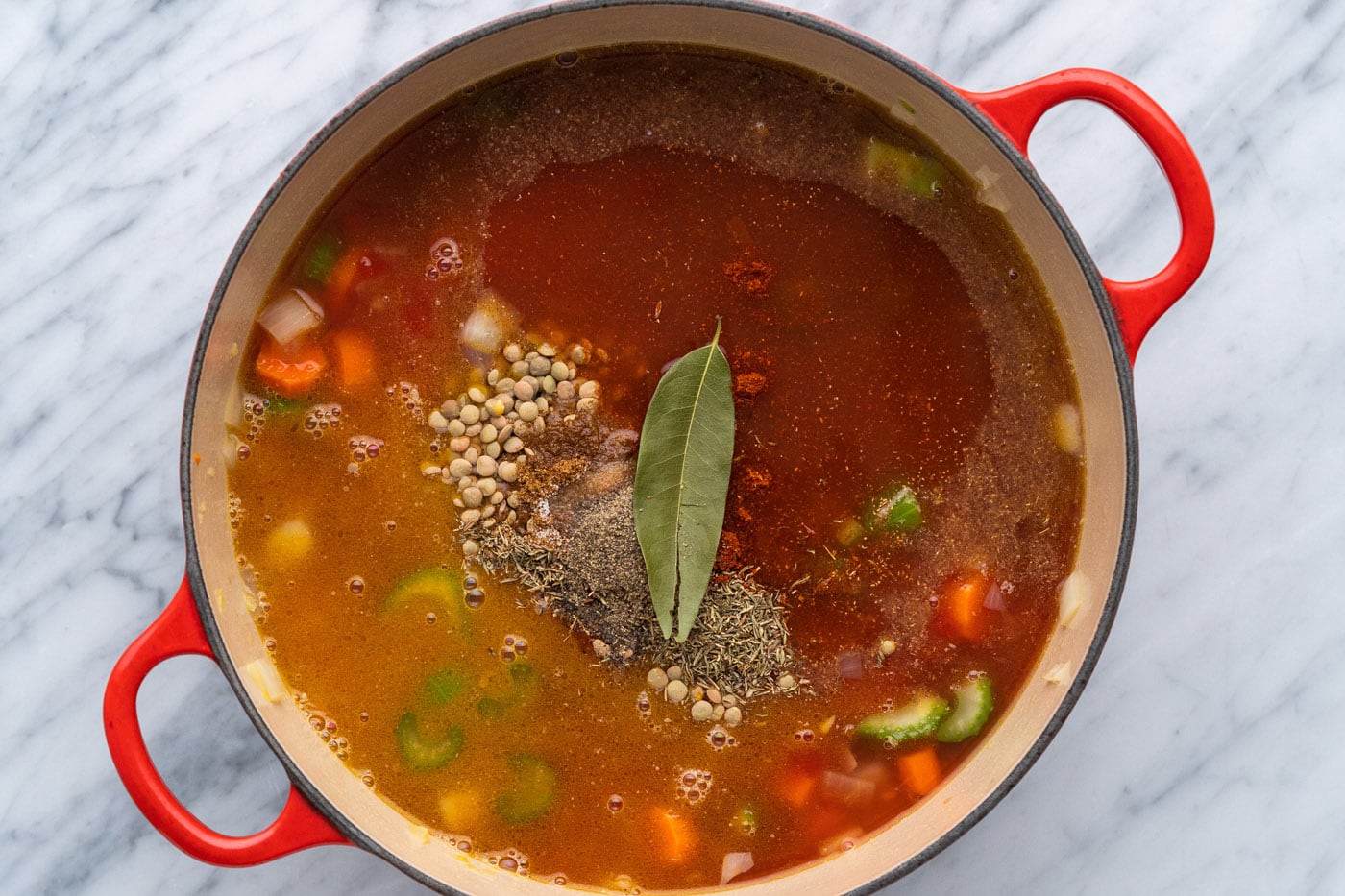 seasonings on top of lentil soup in a pot