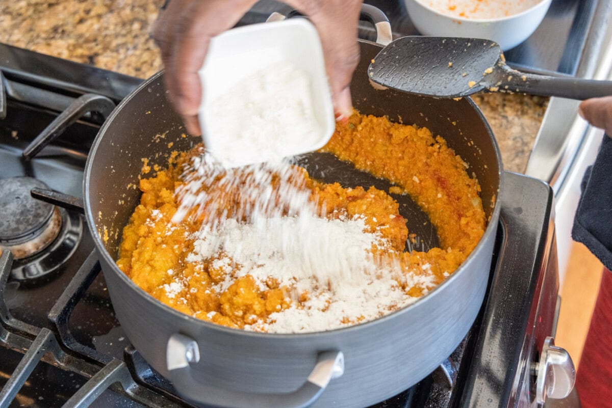 sprinkling flour over lobster bisque mixture in dutch oven