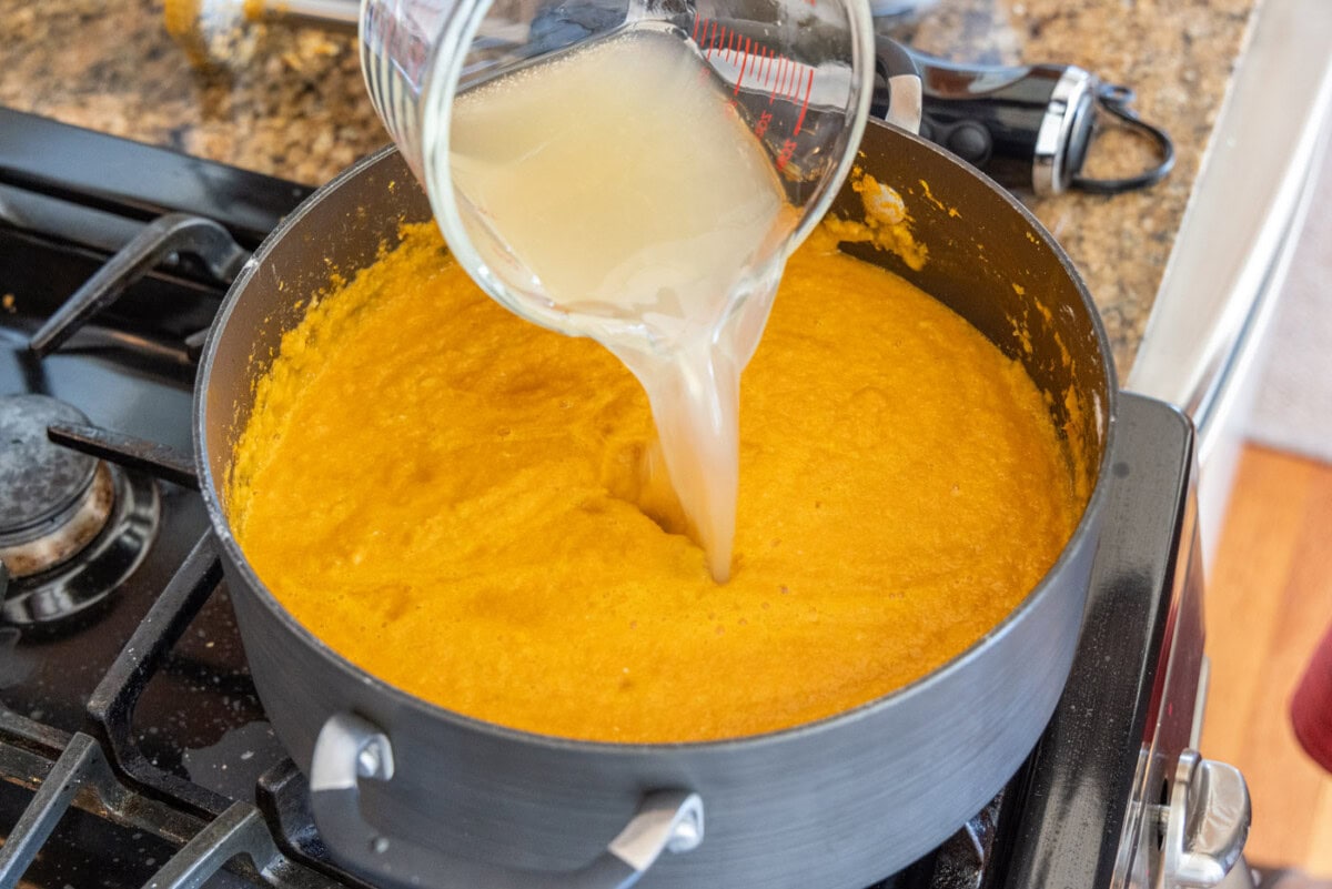 pouring seafood stock into lobster bisque
