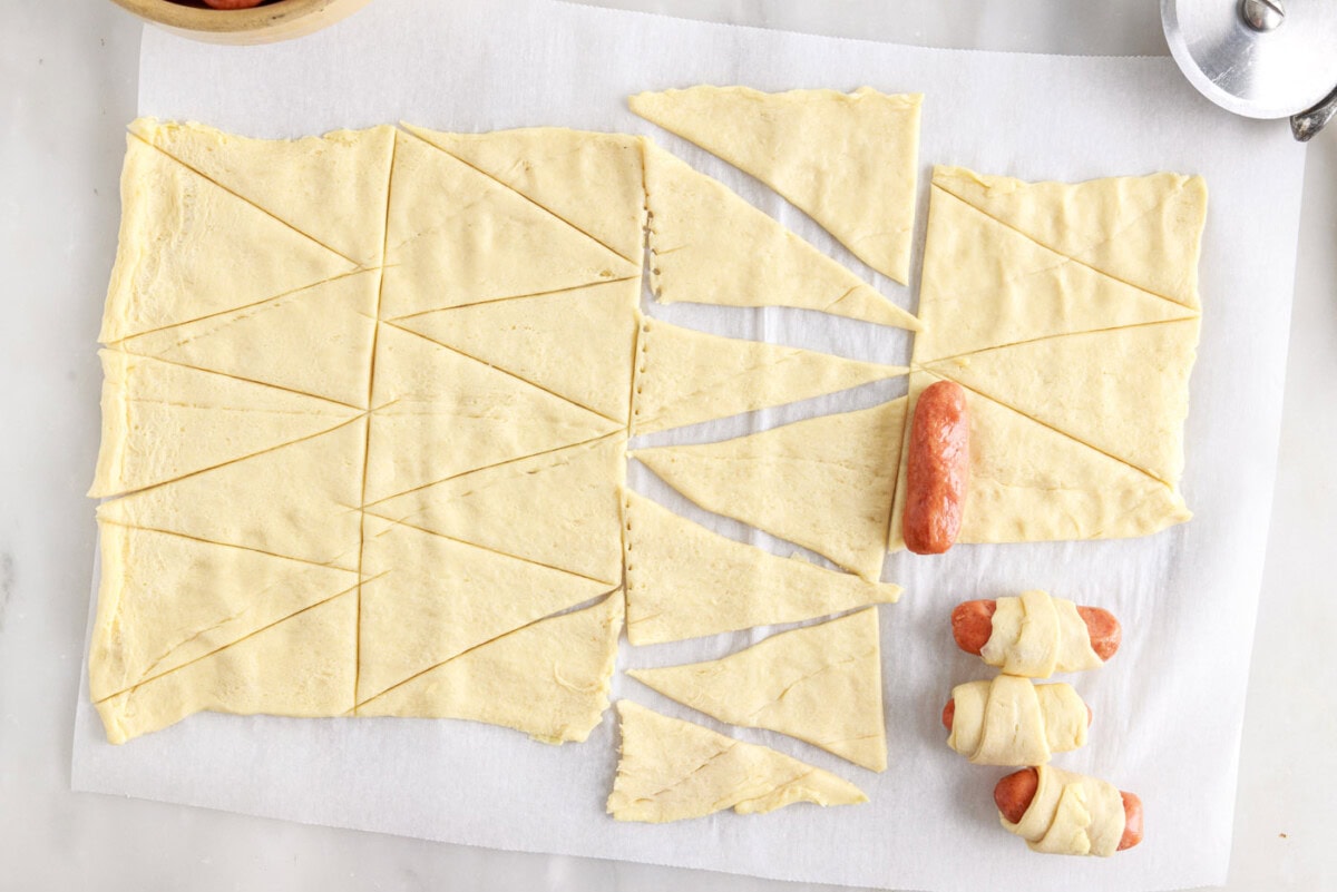 rolling cocktail sausages into crescent dough