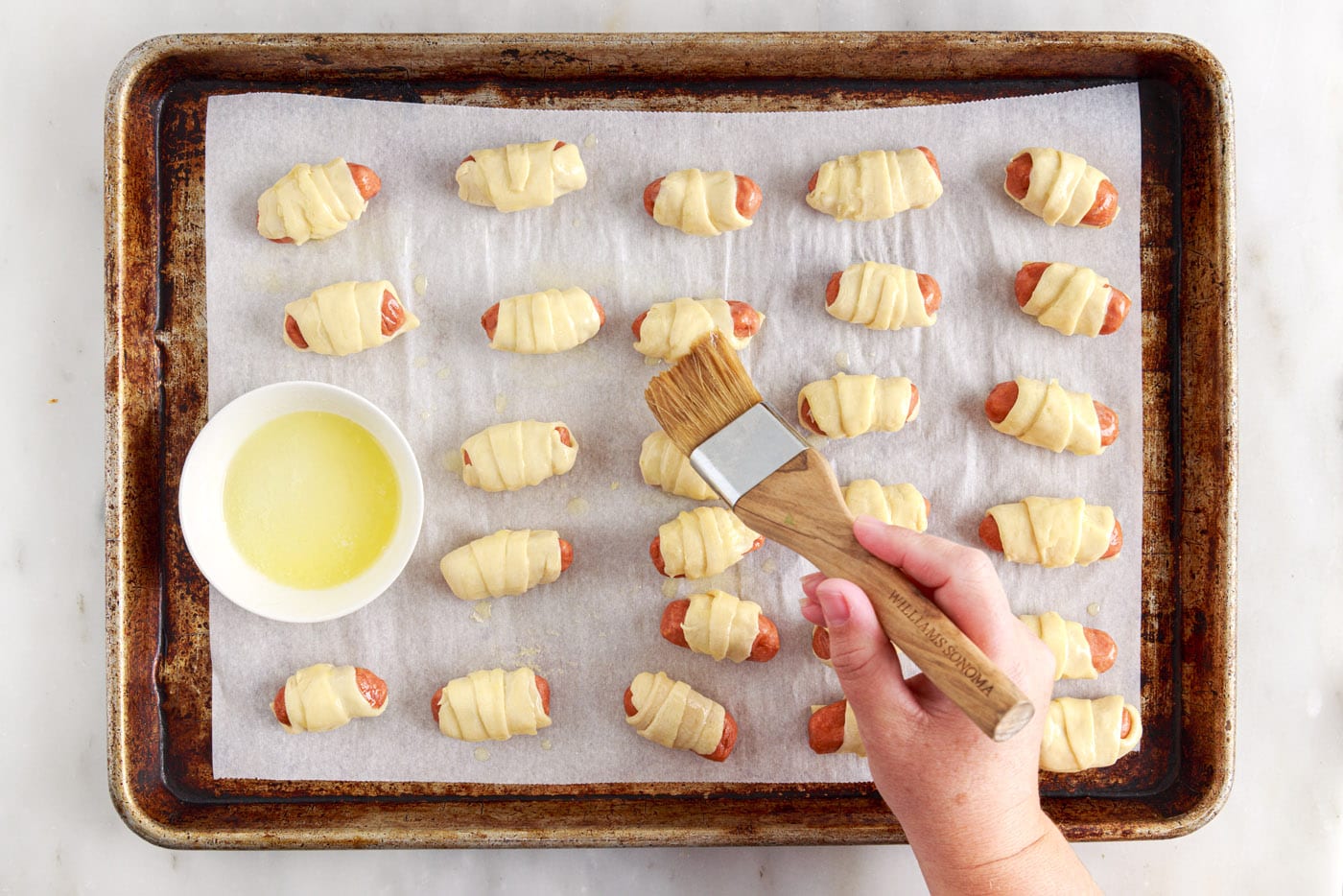 brushing pigs in a blanket with butter