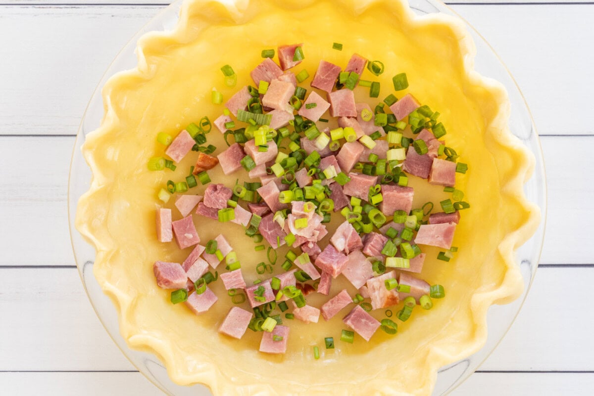 cubed ham and sliced green onions in a pie shell
