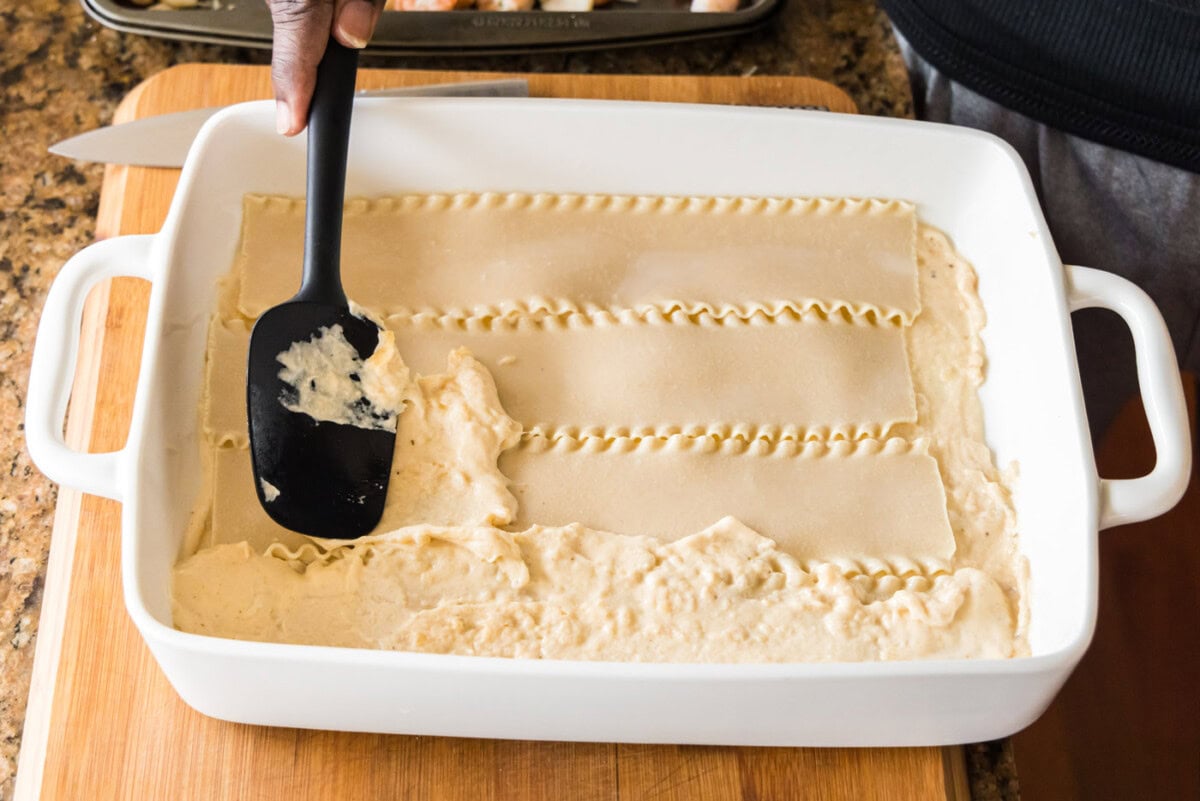 layering sauce on top of seafood lasagna