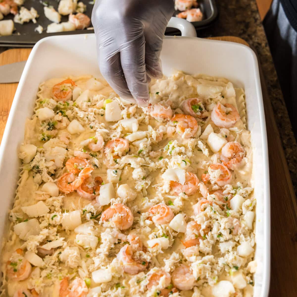 adding seafood meat on top of lasagna noodles
