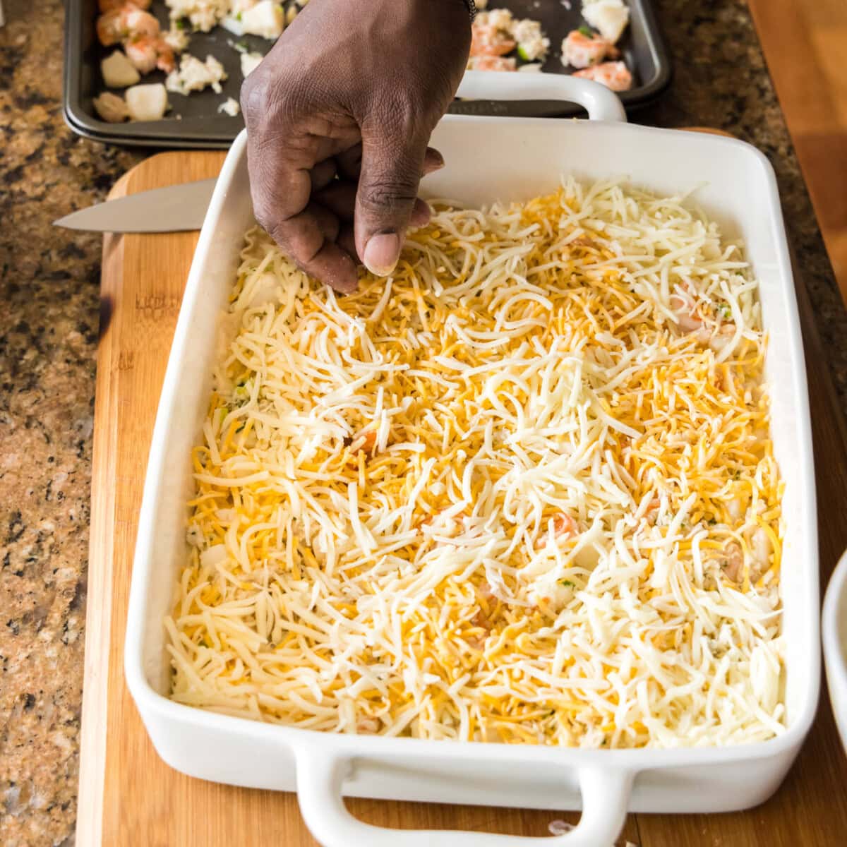 adding cheese on top of seafood lasagna