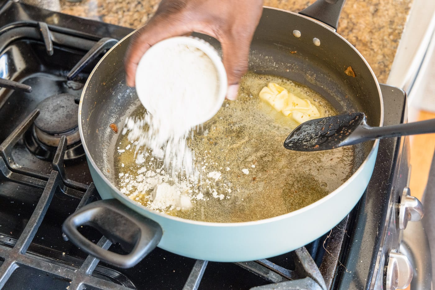 adding flour to make a roux in a skillet