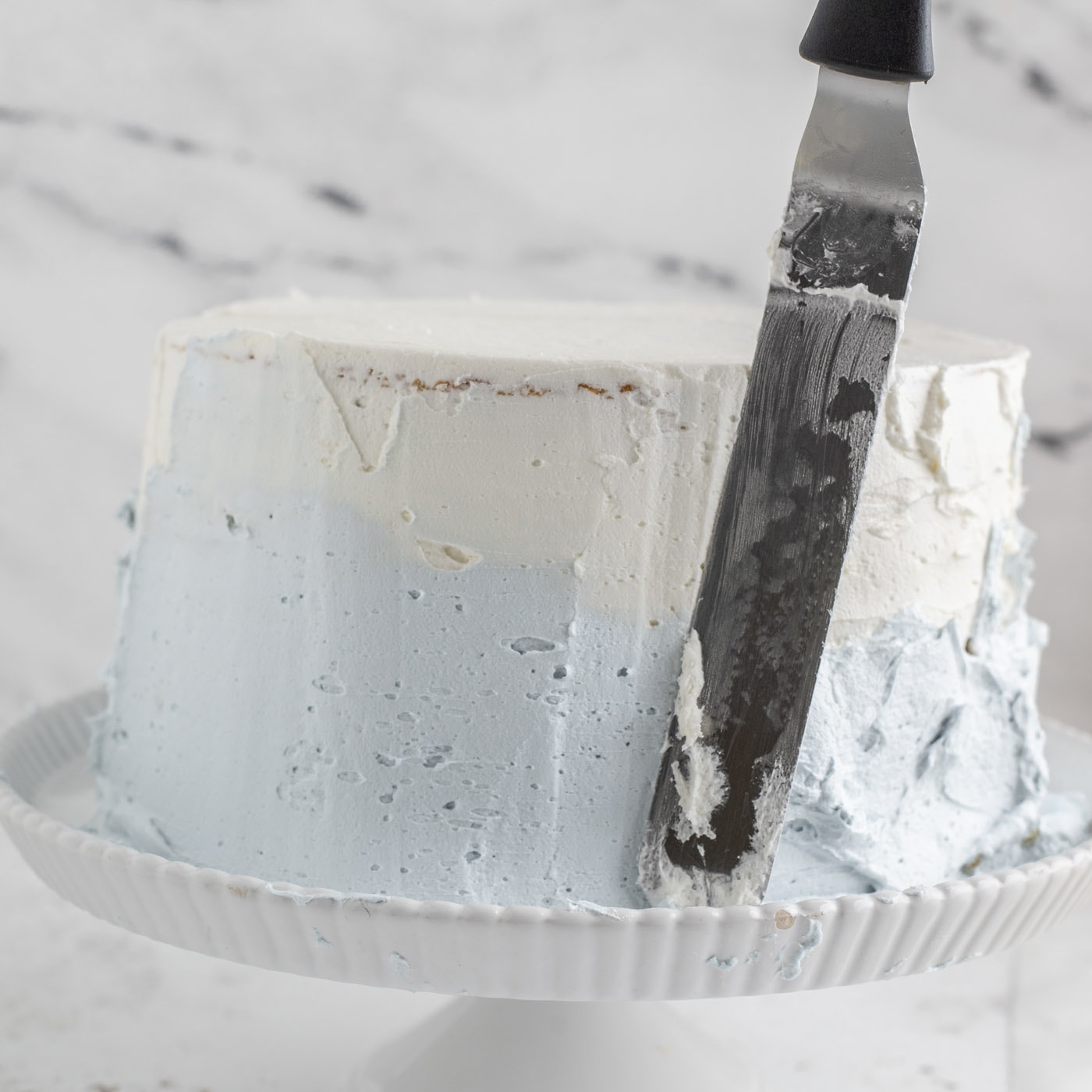 frosting a tiered cake in ombre colors