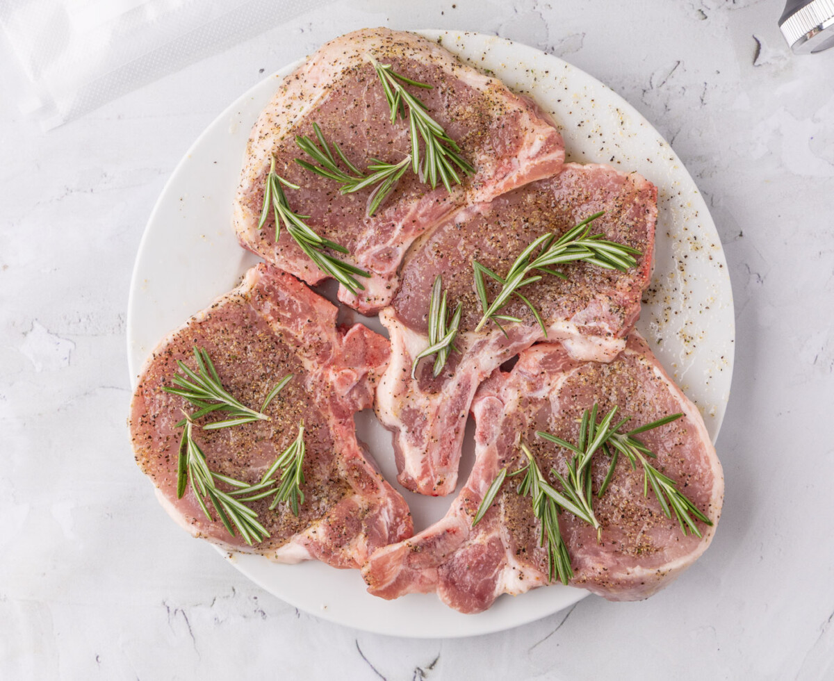 pork chops with rosemary sprigs coated in a wet rub