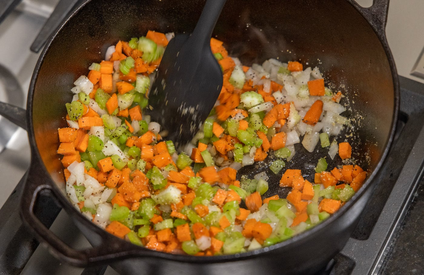 cooking onion, celery, and carrots in a pan
