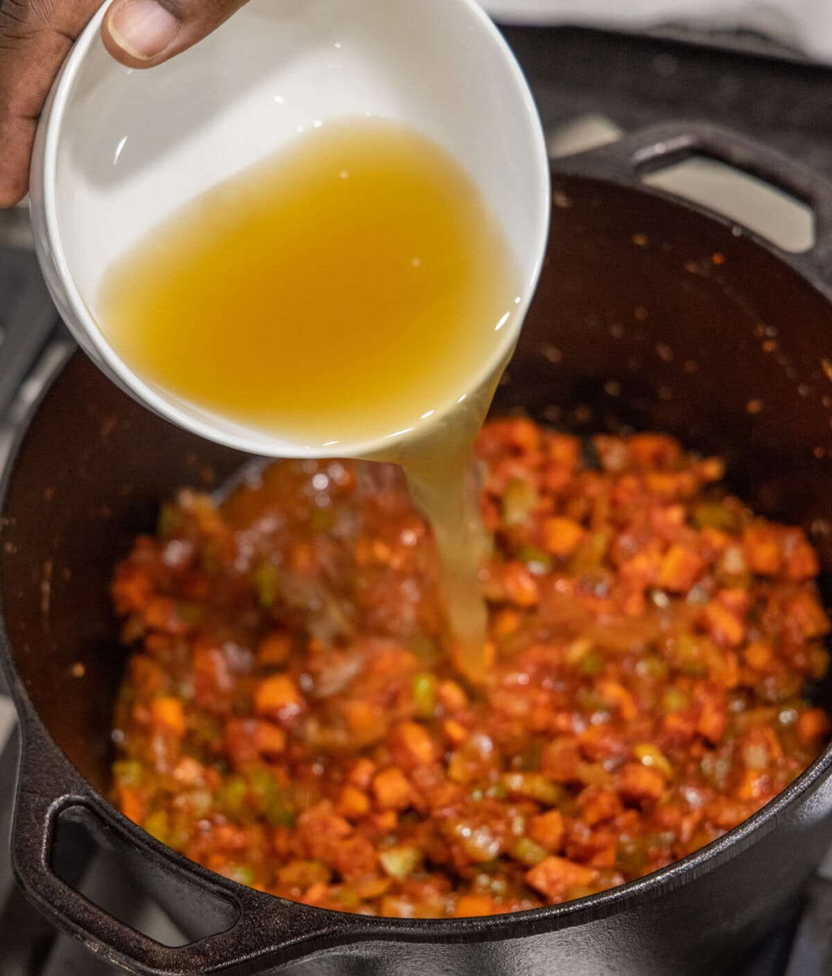 pouring chicken broth into veal osso buco