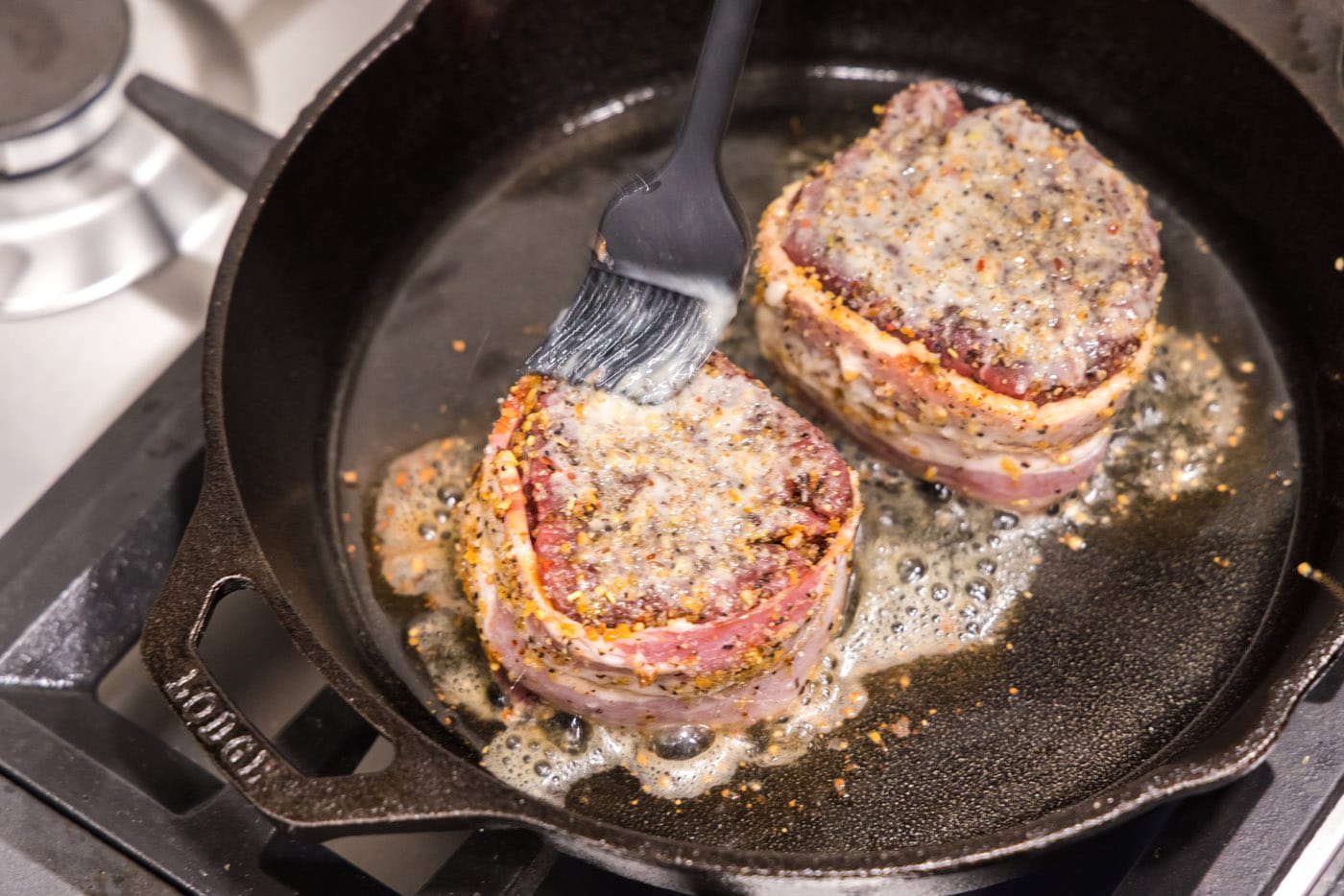 brushing filet mignon with butter in a skillet