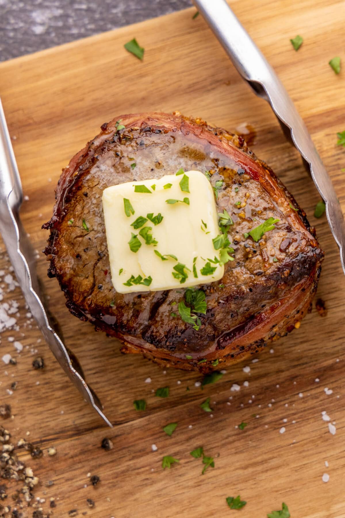 Close up of Bacon Wrapped Filet Mignon on a platter with tongs