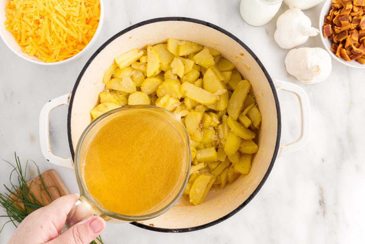 adding chicken broth to potato soup