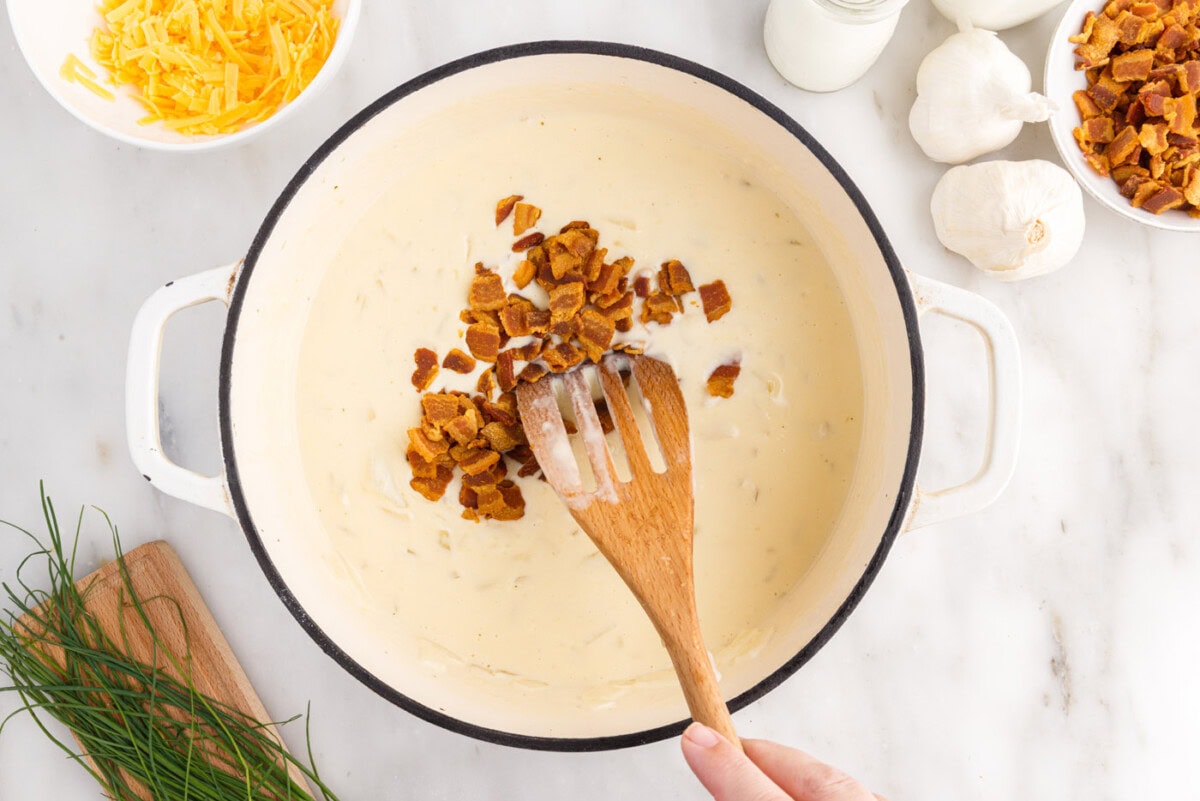 stirring crumbled bacon into baked potato soup