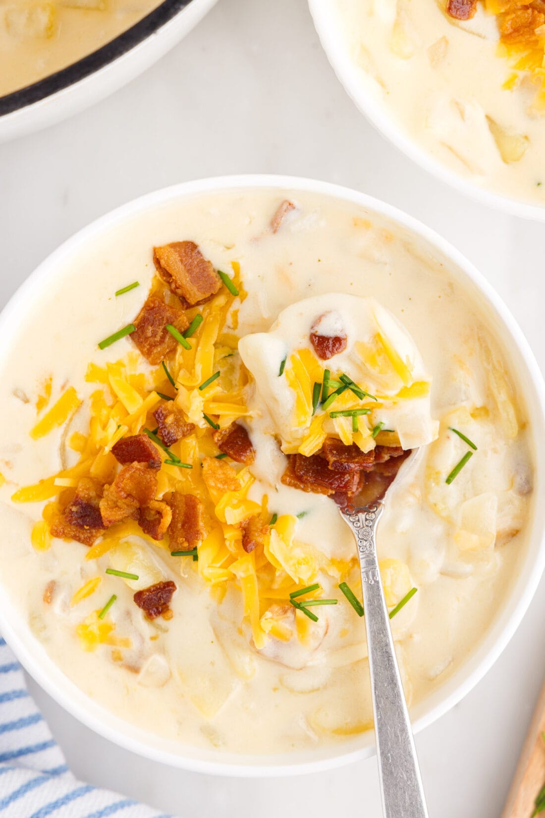 Spoonful of Baked Potato Soup over a bowl of Baked Potato Soup