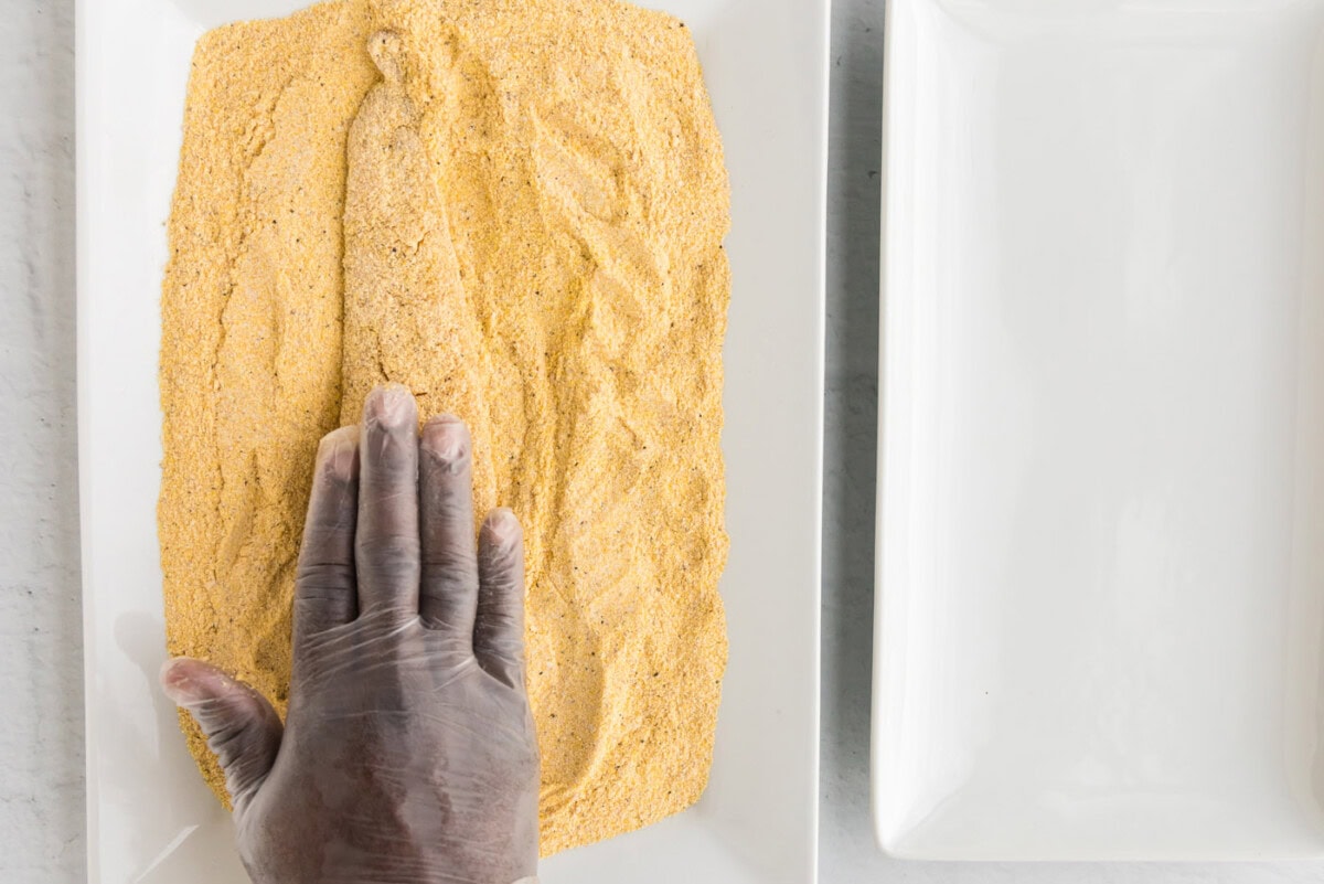 pressing fish into a cornmeal coating