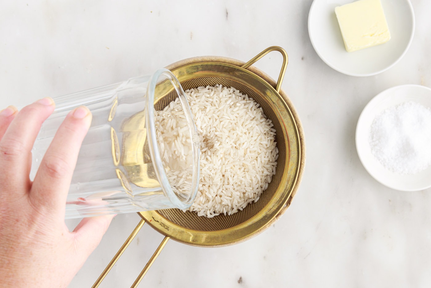 pouring water over white rice in a sieve