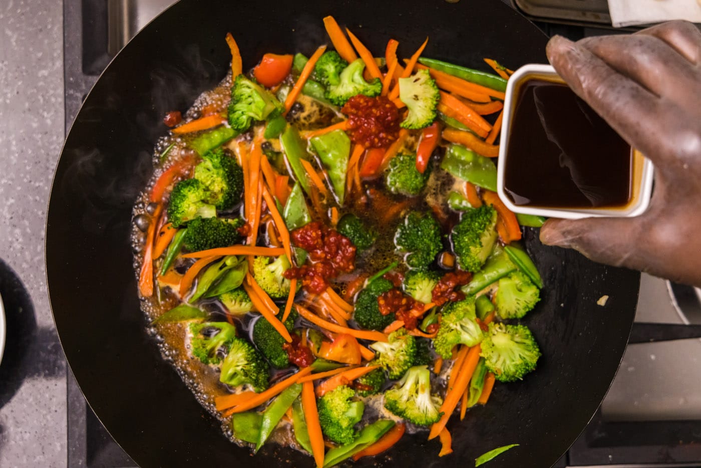 adding soy sauce to stir fried vegetables