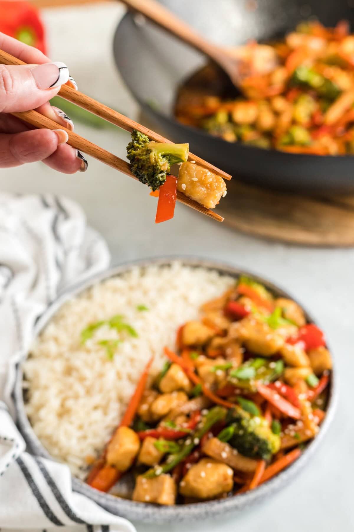 Pieces of Hunan Chicken held in chopsticks 
