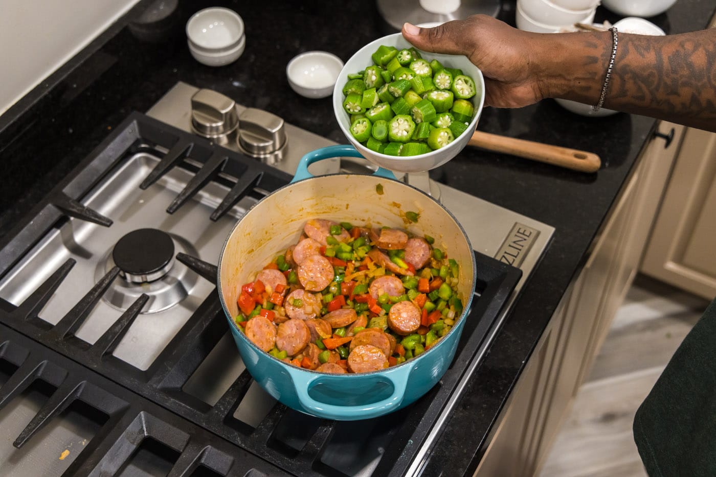 adding okra to pot with smoked sausage and diced vegetables