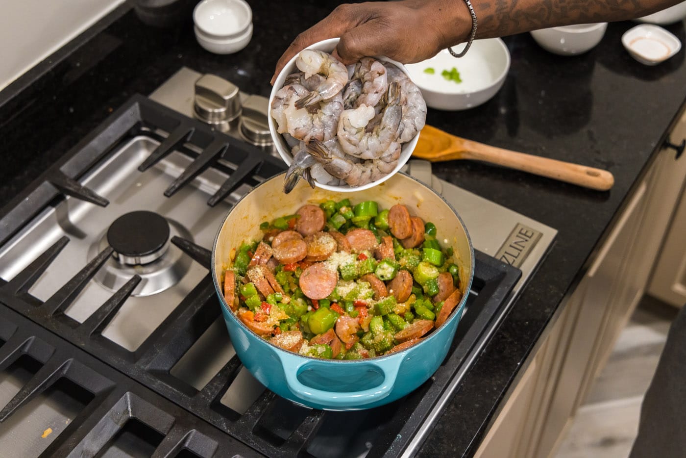 adding shrimp to pot with smoked sausage and holy trinity vegetables