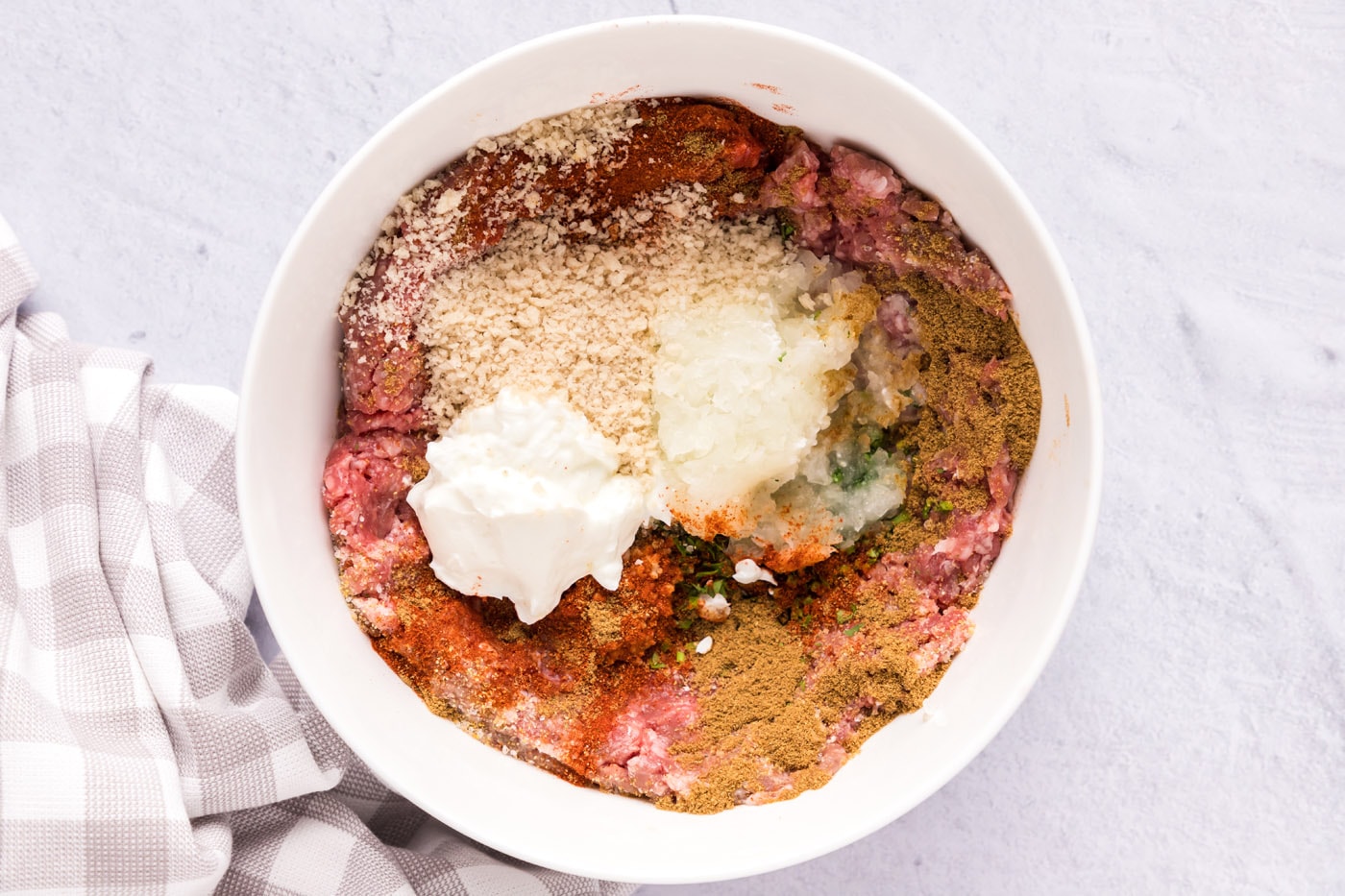 ground lamb with breadcrumbs, seasonings, onion, and greek yogurt in a bowl