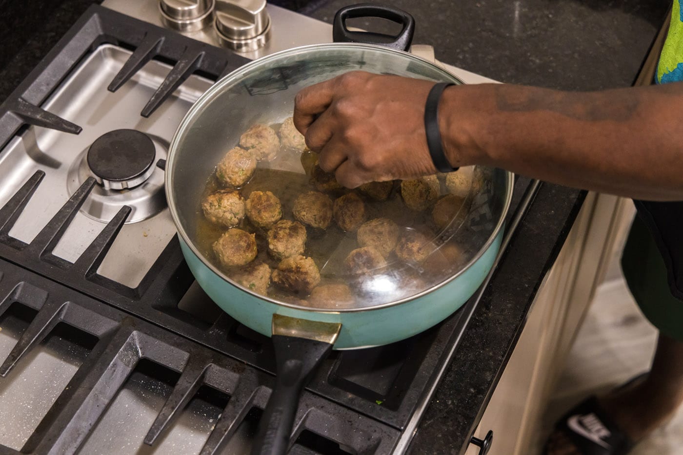 adding a lid to skillet with meatballs