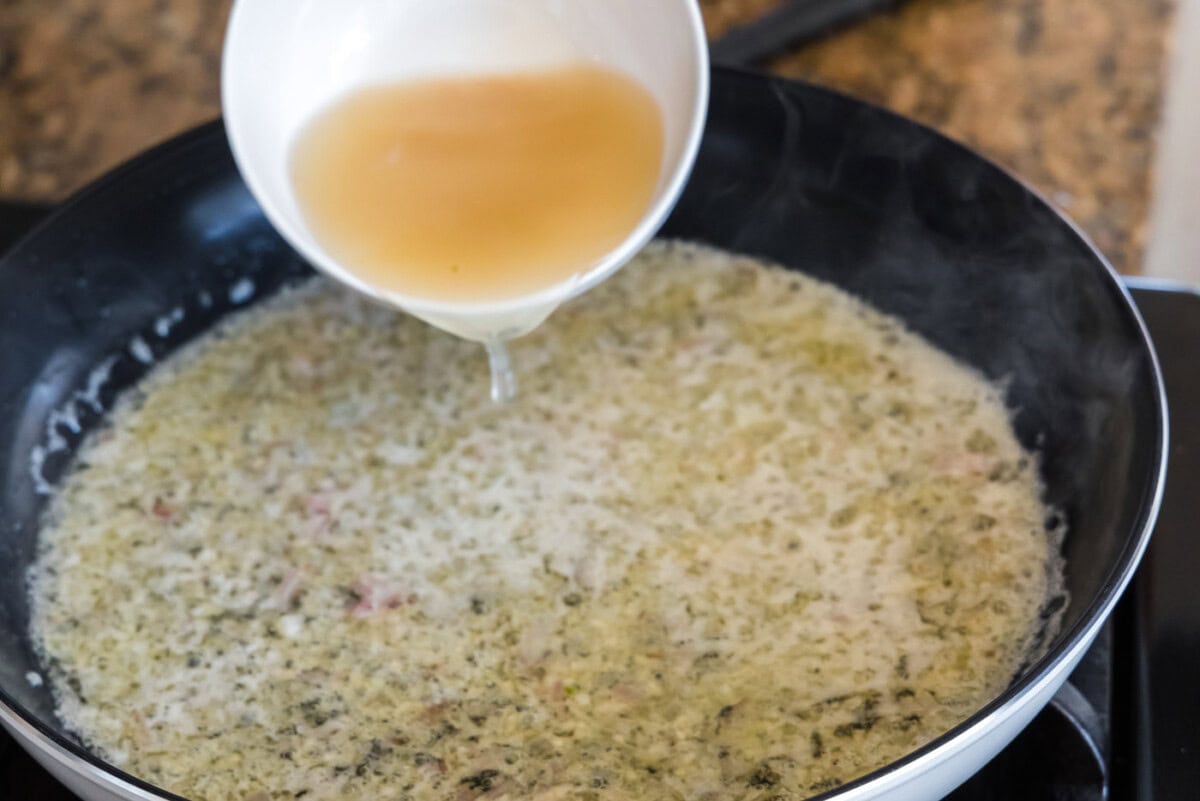 pouring seafood stock into thermidor sauce