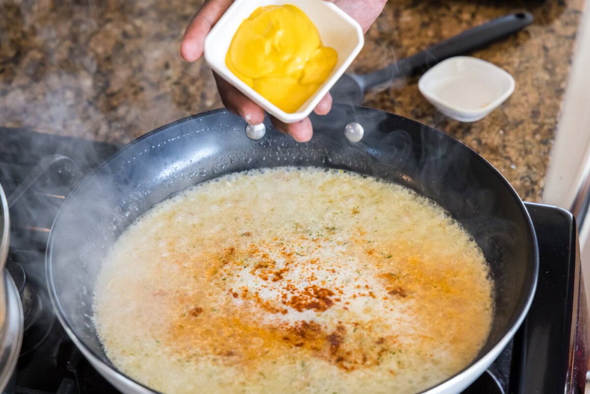 adding yellow mustard to lobster thermidor sauce