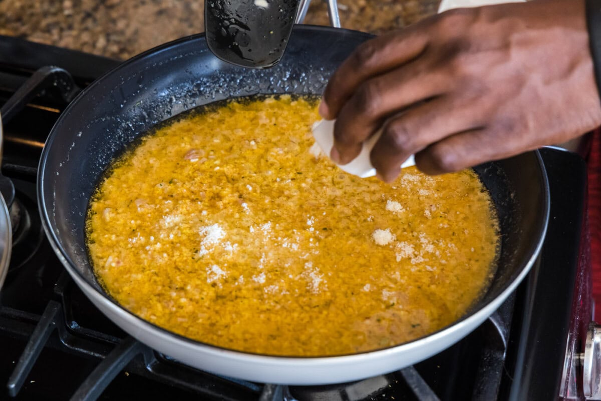 sprinkling parmesan cheese into thermidor sauce