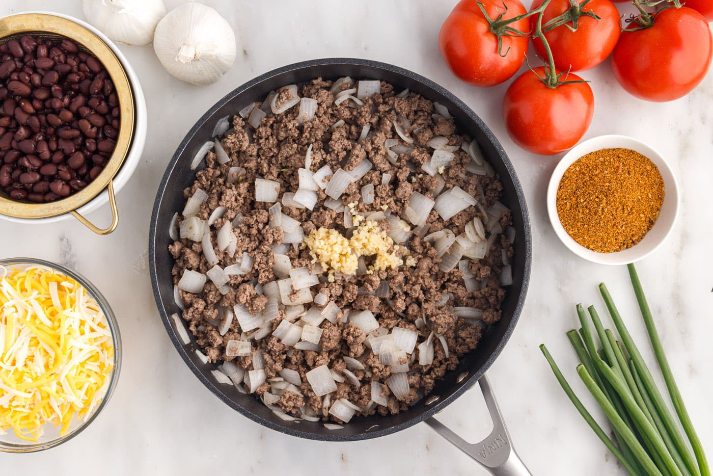 adding garlic to ground beef and onion in a skillet