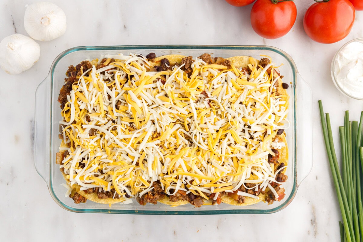 Shredded cheese on top of corn tortillas and beef mixture