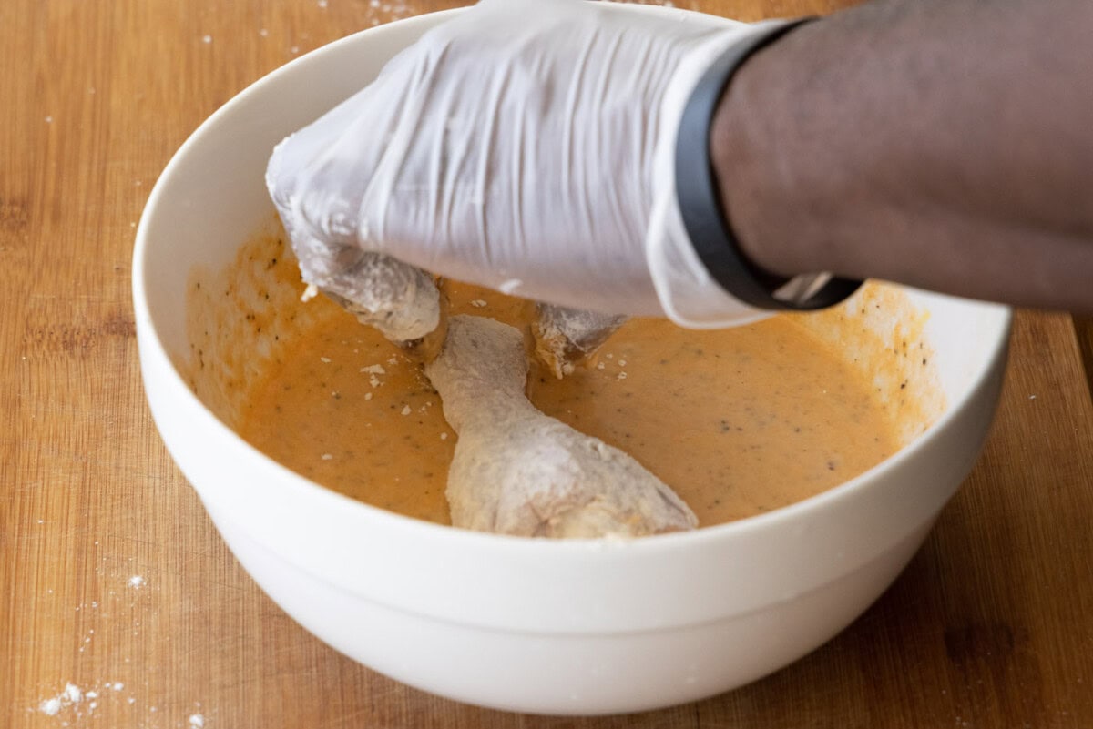 dipping chicken legs in spiced egg mixture