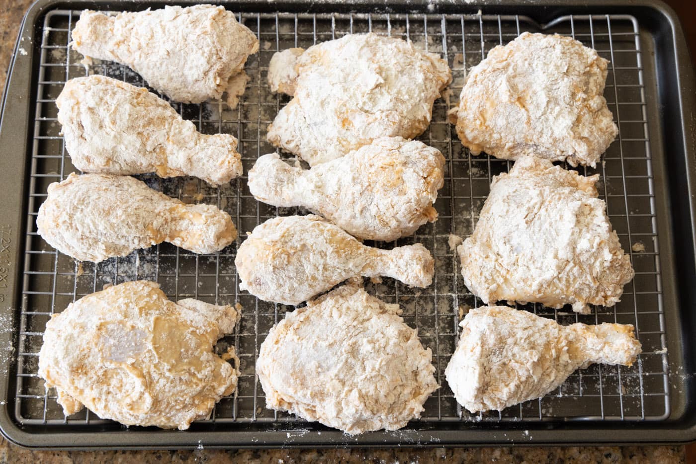 flour and egg dredged chicken thighs and legs on a baking sheet